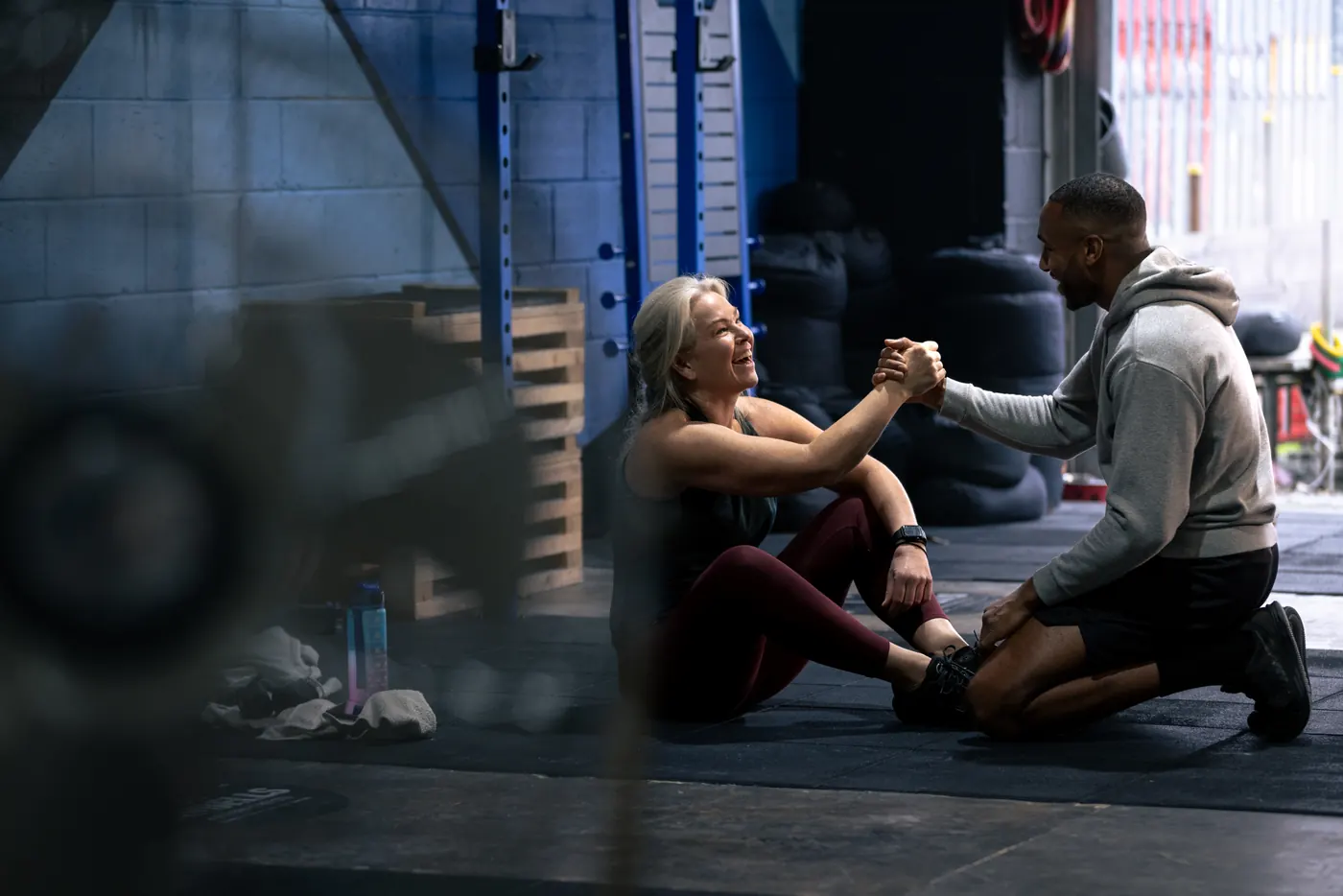 A coach helping a client up from the floor during a gym session