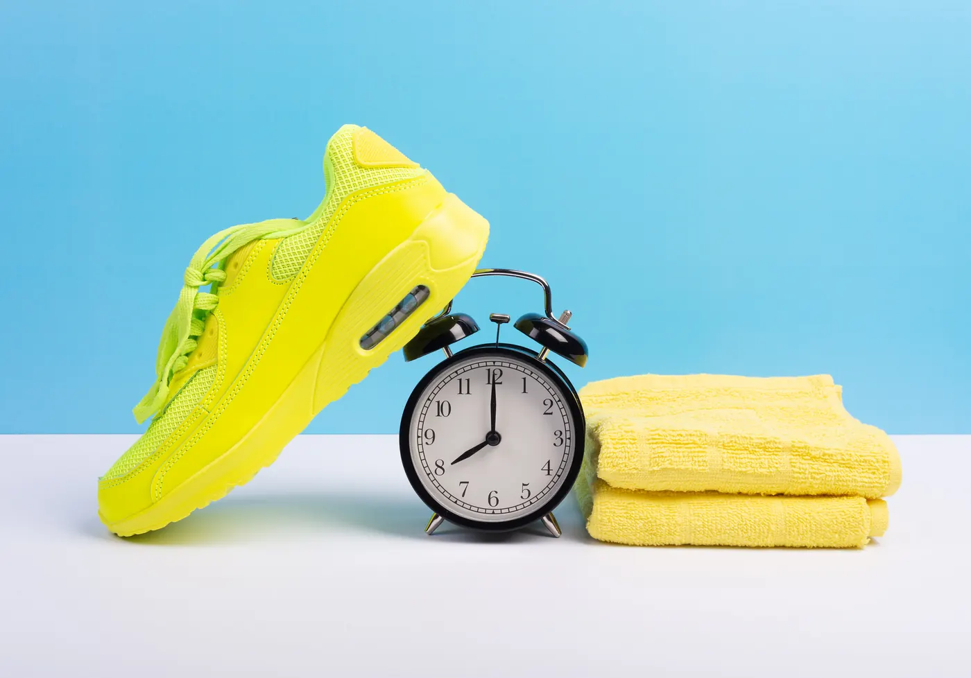 Running shoes, a towel and an alarm clock against a blue background